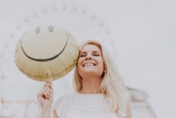 Image of a happy woman holding a balloon with a happy face - Positivity